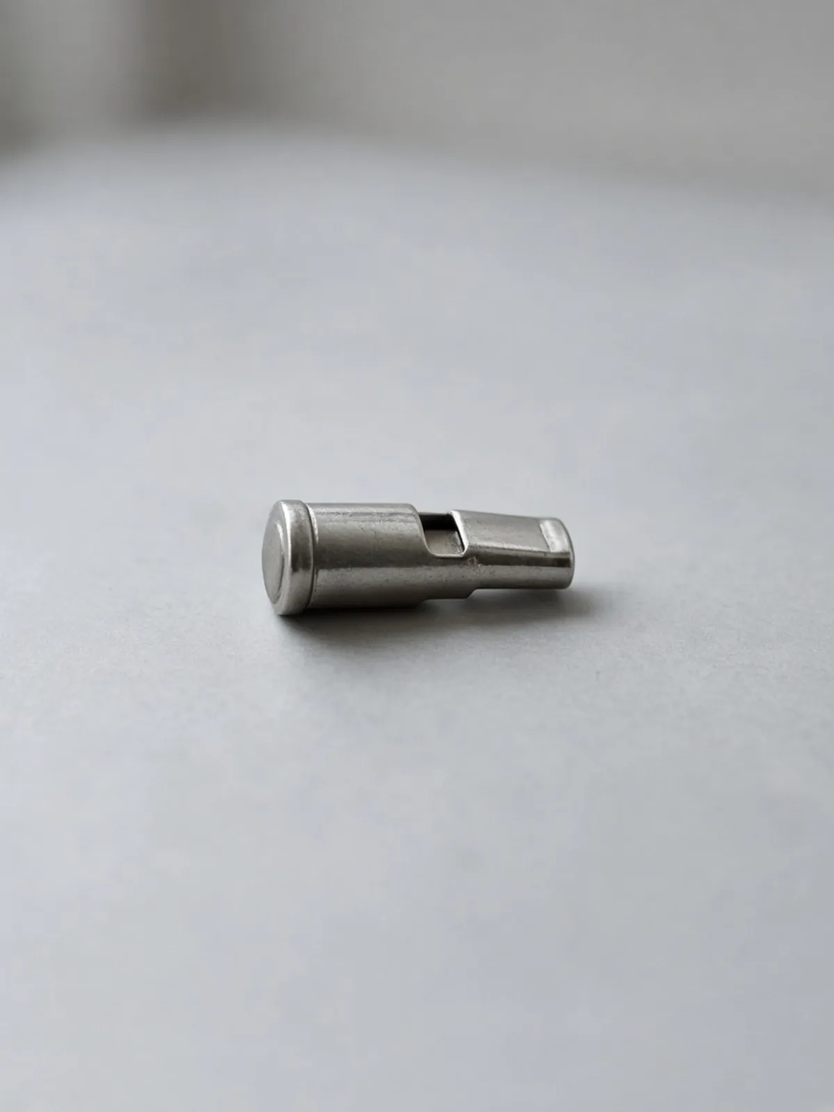A metal whistle on a cord lying on a desk