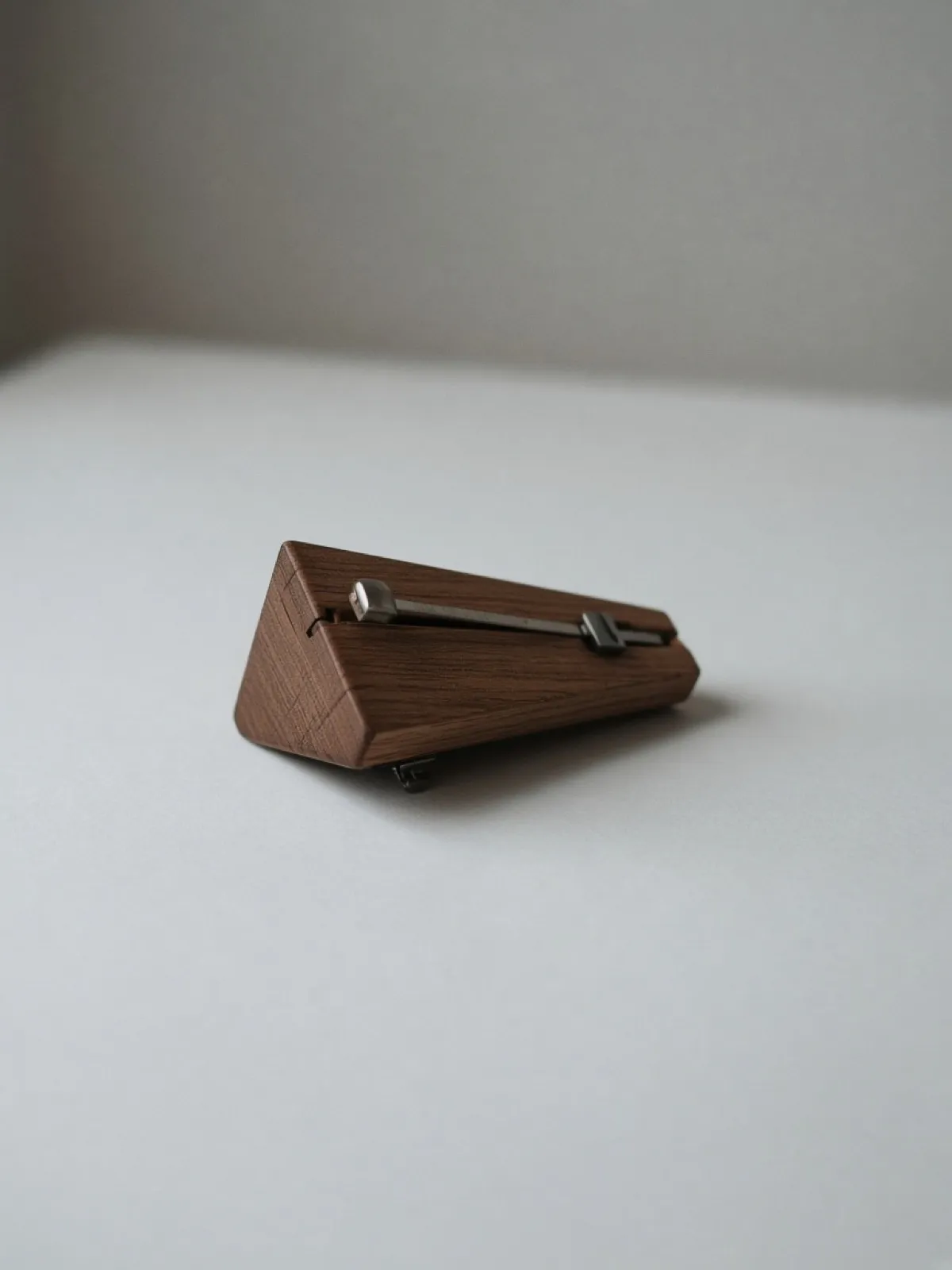 A wooden metronome lying on its side on a desk
