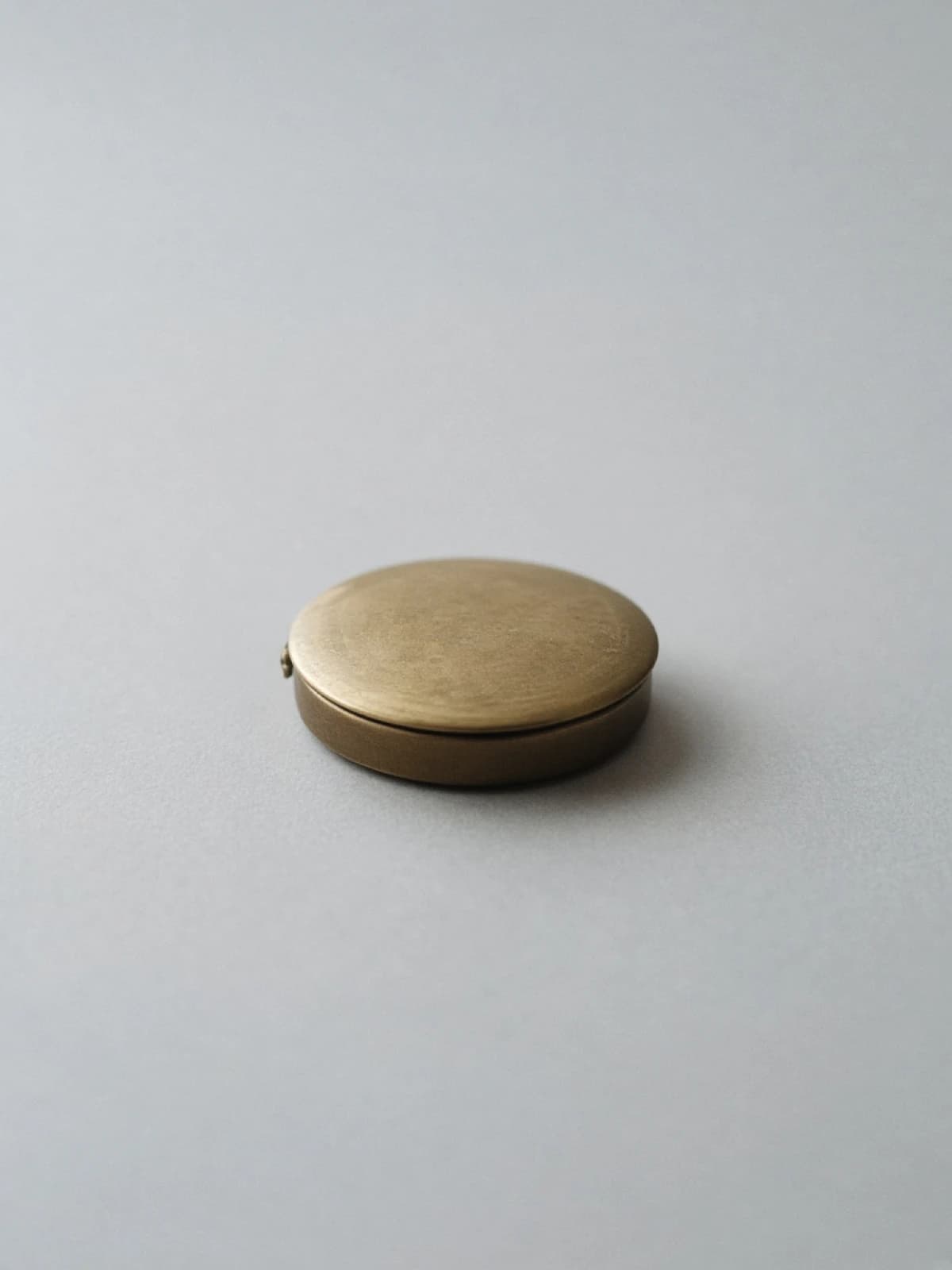 A closed brass pocket watch lying on its side on a desk