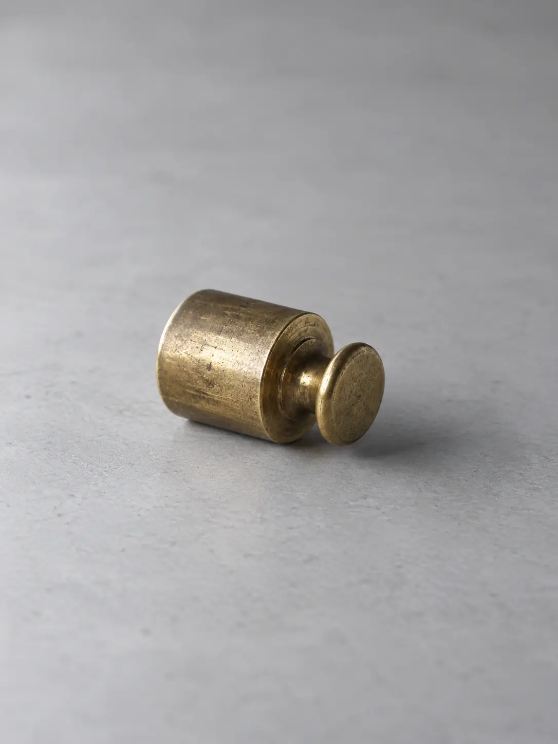 A brass calibration weight lying on a desk
