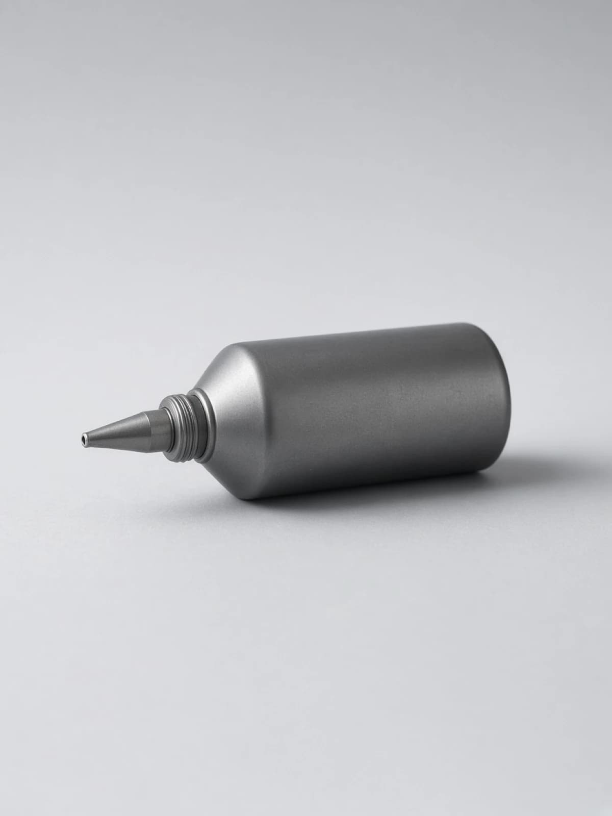A small steel oil can lying on its side on a desk