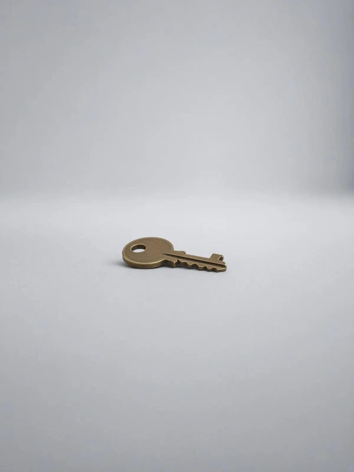 A brass house key lying on its side on a desk