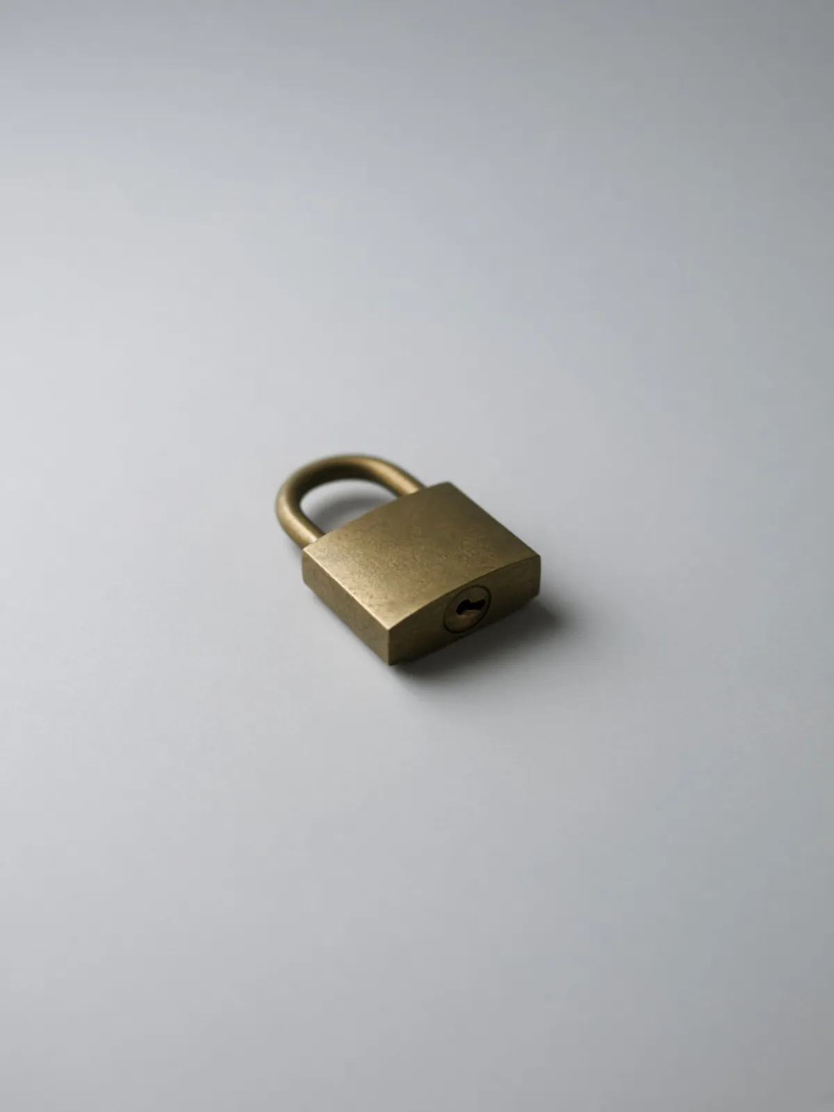 A small brass padlock lying on its side on a desk