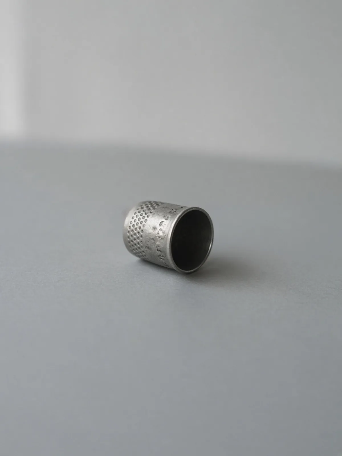 A small metal thimble lying on its side on a desk