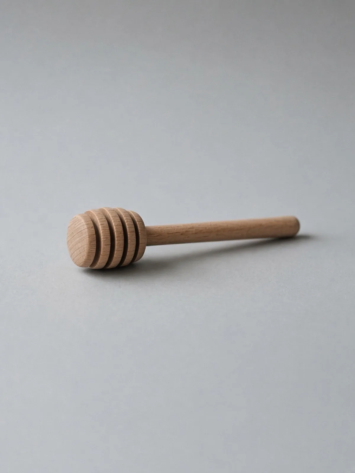 A wooden honey dipper lying on its side on a desk