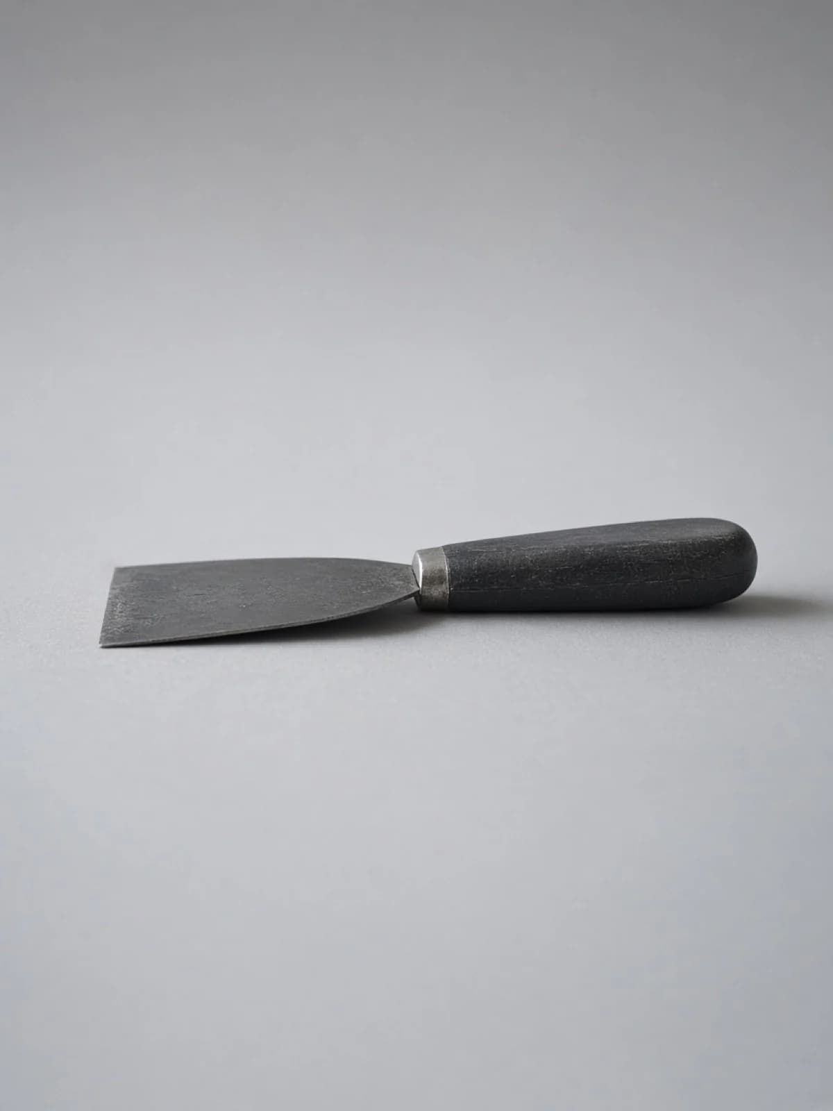 A putty knife lying on its side on a desk