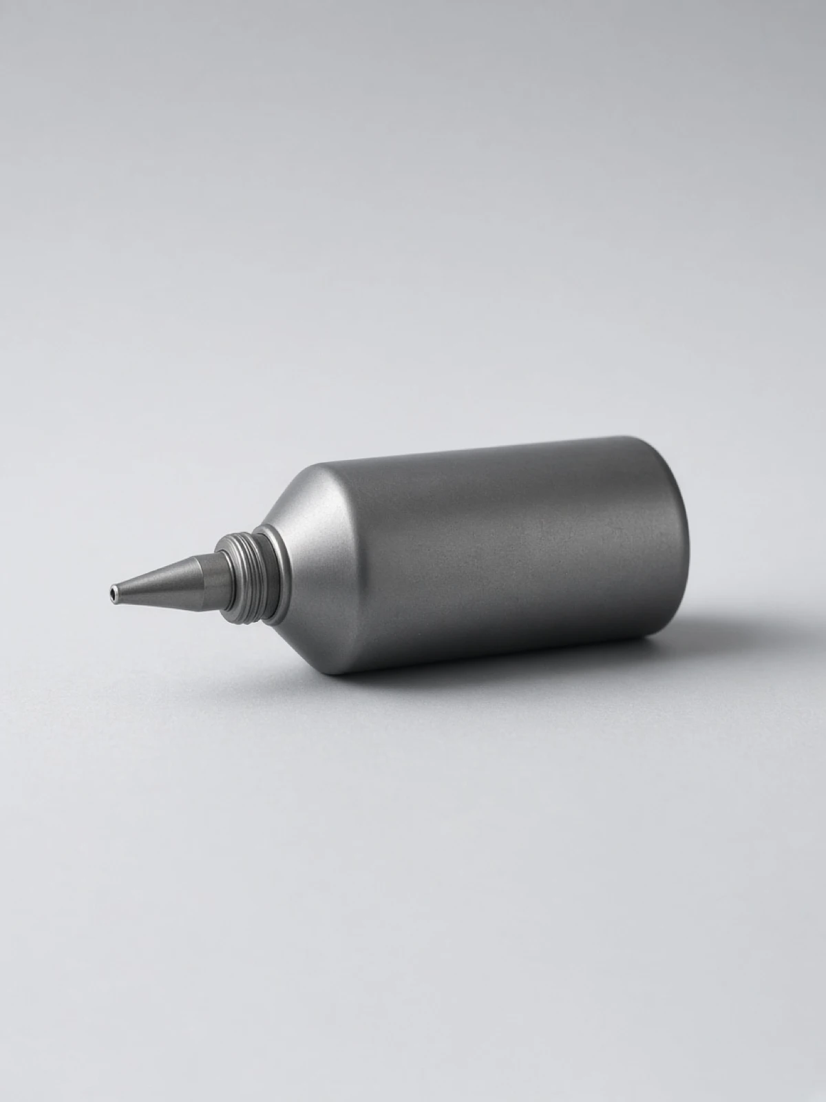 A small steel oil can lying on its side on a desk