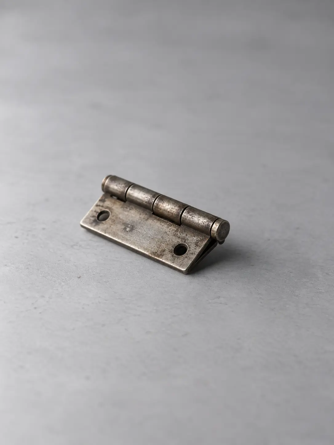A metal door hinge lying on a desk