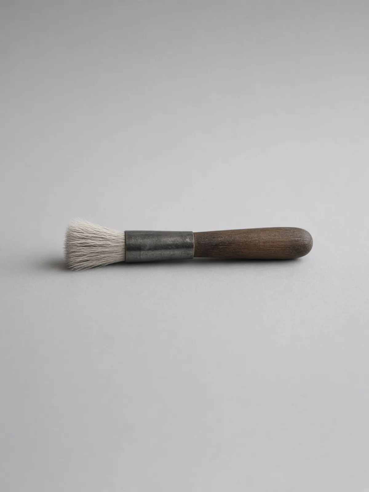 A wooden-handled paintbrush lying on its side on a desk