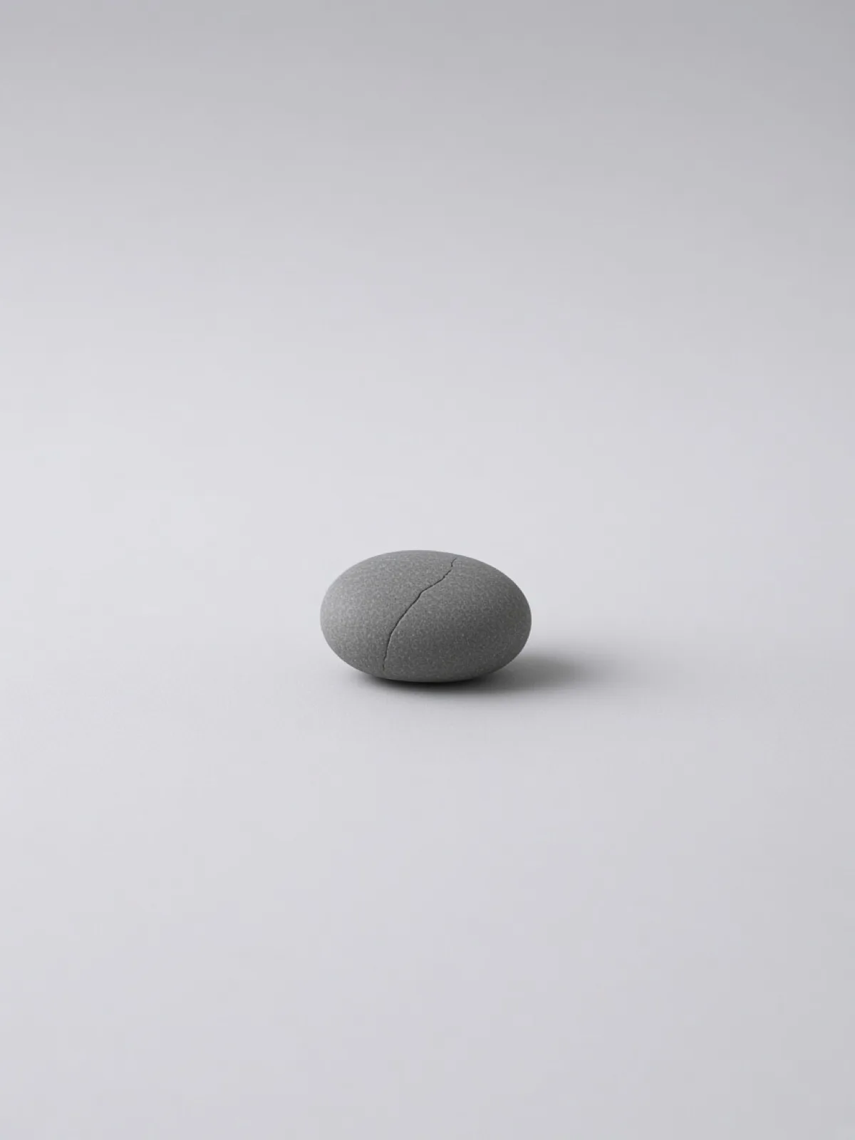 A gray river pebble with a hairline crack on a desk