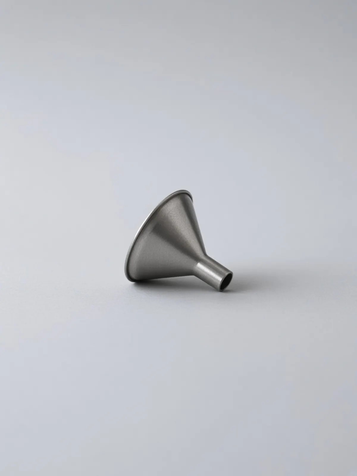 A small steel kitchen funnel lying on its side on a desk