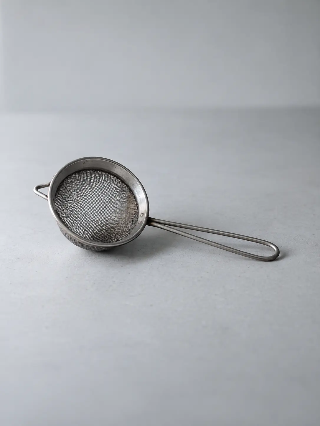 A tea strainer lying on its side on a desk